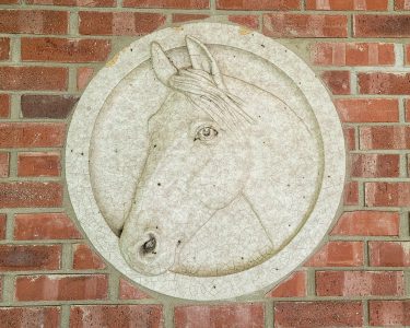 A relief carving of a horse's head inlaid in a brick wall.